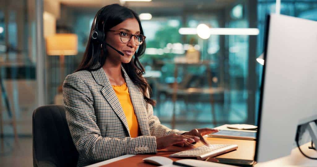 Business woman wearing a headset and typing on the computer